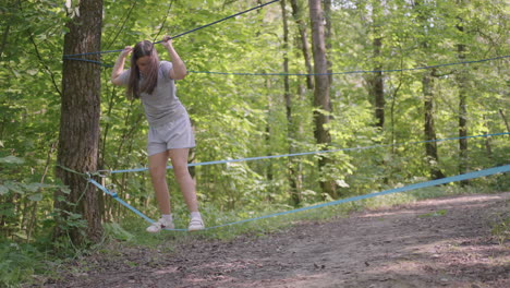 Small-girl-in-climbing-equipment-in-a-rope-Park.-Group-of-Caucasian-children-training-at-boot-camp.-In-the-children-camp-children-are-taught-to-overcome-obstacles-with-the-help-of-a-rope-crossing